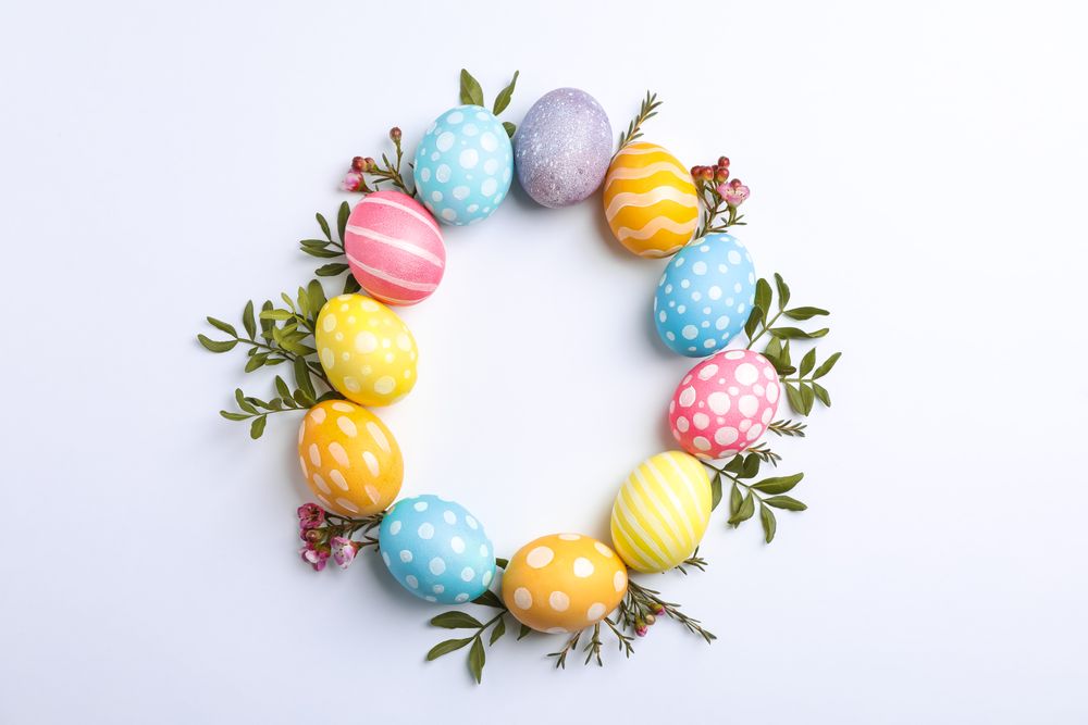 Decorative Easter eggs and flowers on neutral background, space for text. Top view