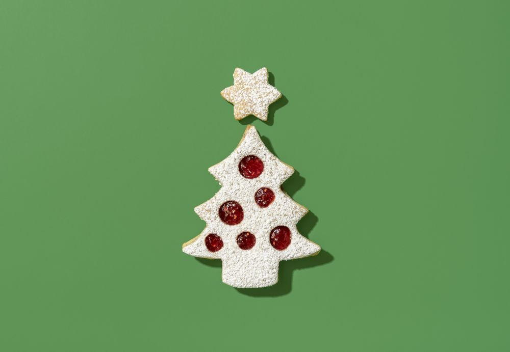 Christmas tree shaped cookie on a green background, top view