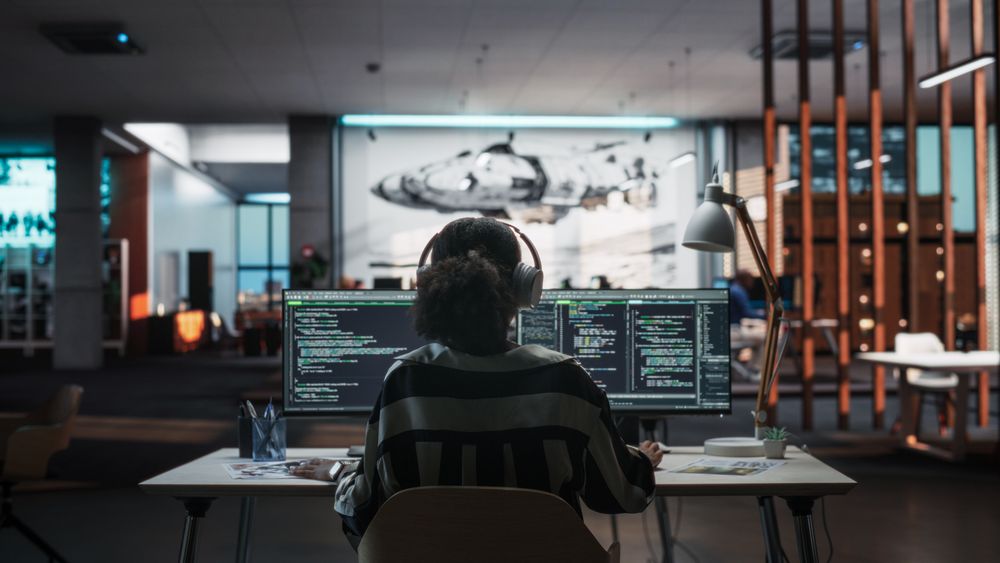 Creative Office: Professional Black Female Programmer Uses Headphones, Working on Desktop Computer.