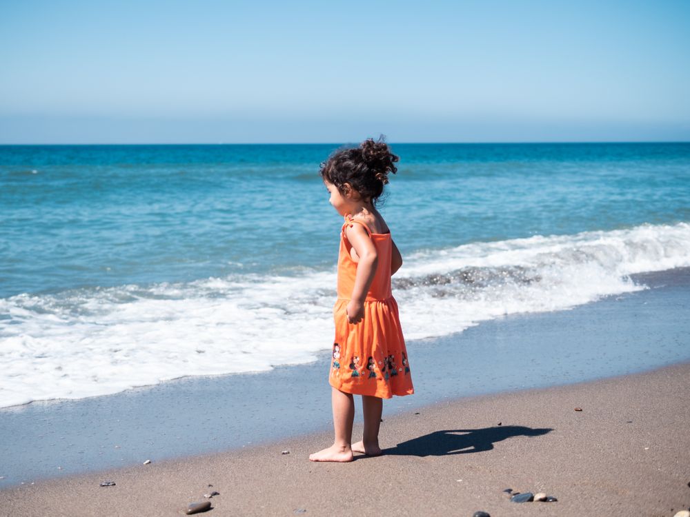 Little girl standing on beach and admiring view