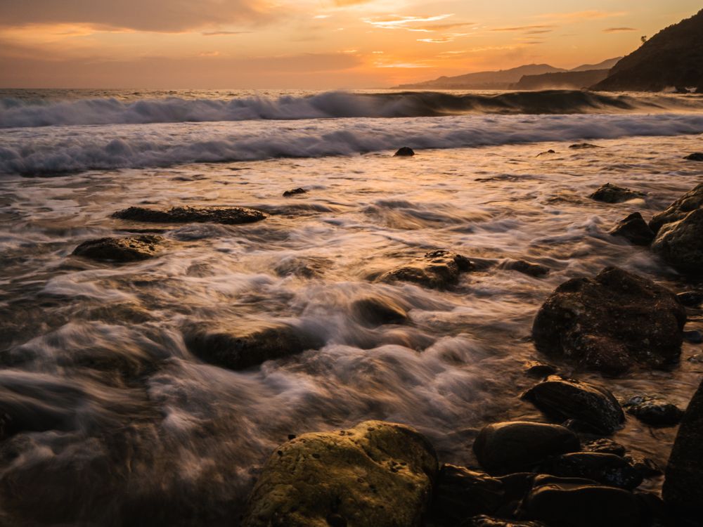 Stony seashore and waves at beautiful sunset