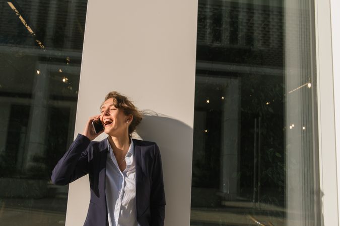 Cheerful female manager speaking on smartphone on street