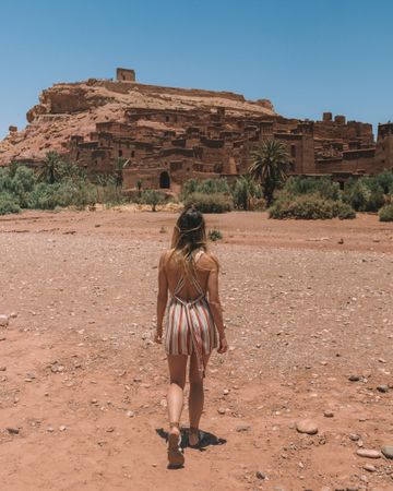 Woman walking in desert with ancient city