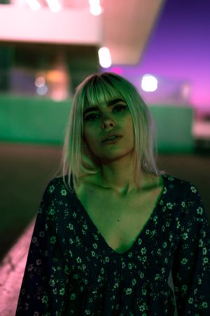 Magnificent pensive adult woman looking at camera against vibrant sky at dusk