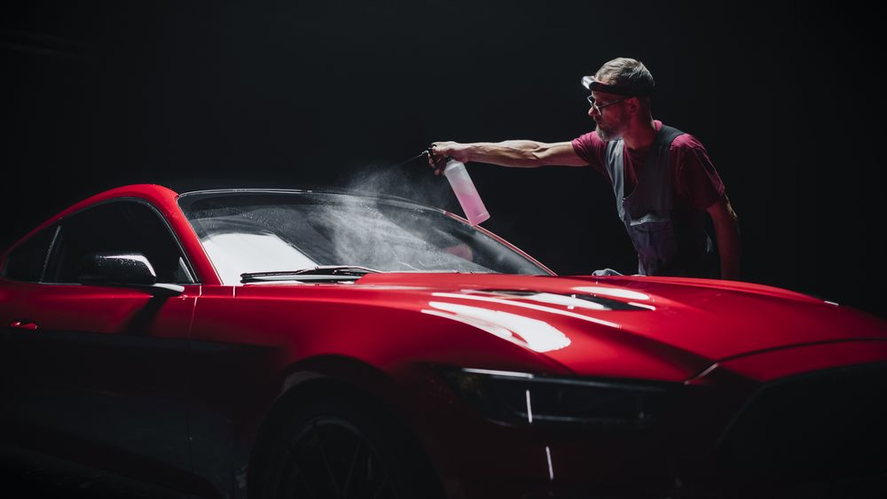 Portrait of a Car Detailer Spreading a Chemical Wax Solution for Polishing a Windshield and Protecting the Glass from Steaming Up During the Rain.