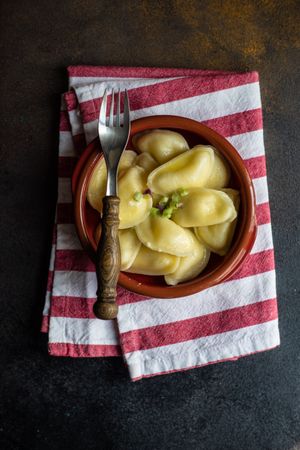 Top view of bowl of traditional Ukrainian vareniki on striped napkin