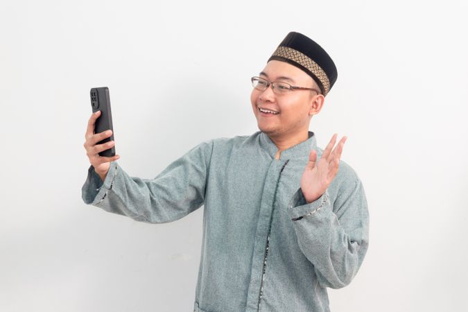 Happy Asian Muslim man holding phone and video call in Ramadan