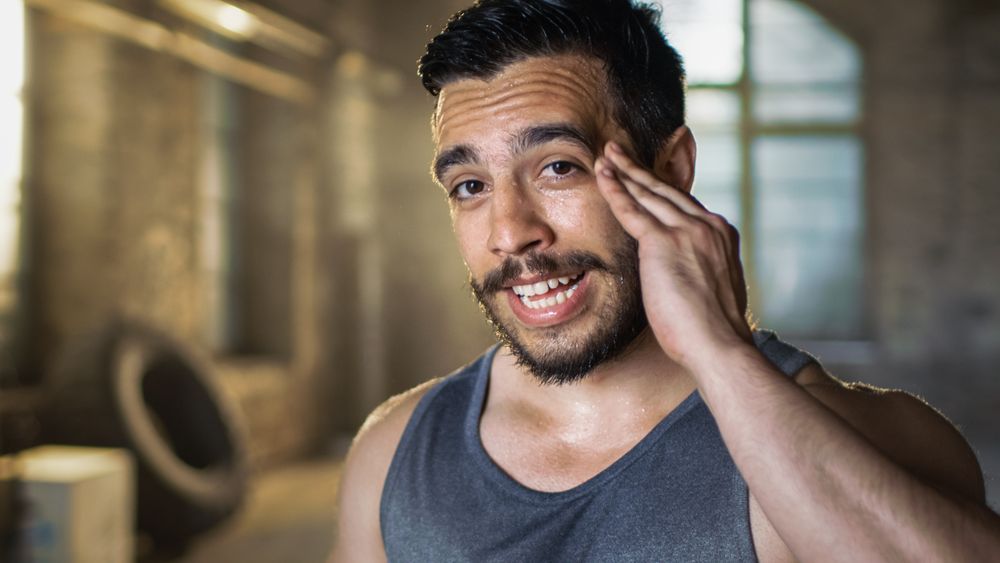 Muscular Man Wipers Sweat of His Forehead after Intensive Cross Fitness Bodybuilding Training.