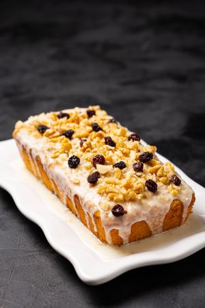 Fruit cake topped with icing, walnuts and raisin