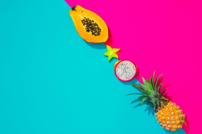 Tropical fruit, pineapple, papaya, dragonfruit on bright blue and pink background