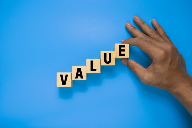 male hand put wooden blocks with value word isolated on blue background