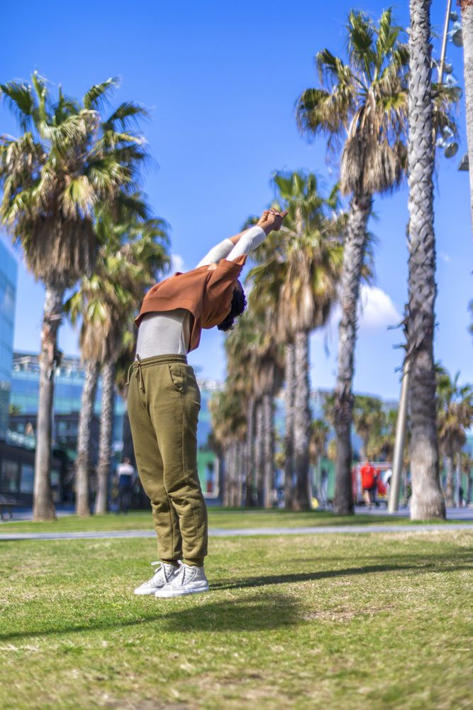Black woman stretching back under the palms in a promenade