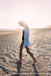 Woman walking on beach with her head down in oversized shirt 43Prjb