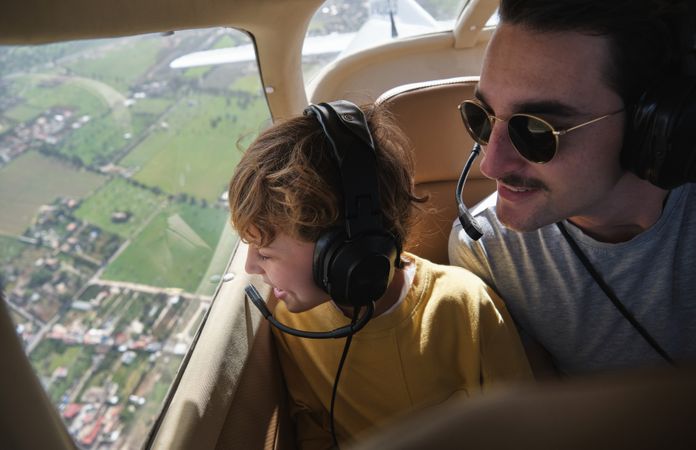 Positive young father with preteen son sitting in aircraft cabin