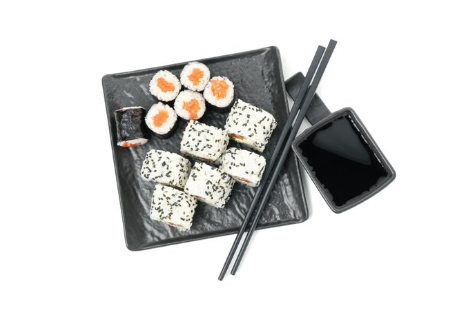 Tray with sushi rolls, chopsticks and soy sauce isolated on light background