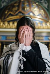 Jewish man wearing suit and Kittel praying in synagogue 4OXevb