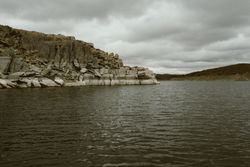 Rocky mountain on high seas in grey day