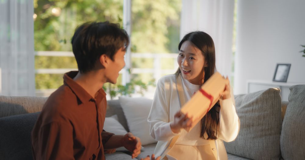 Boyfriend Surprising His Partner with Two Gifts Wrapped in Festive Design.