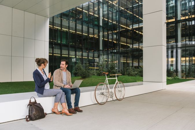 Cheerful colleagues using laptop on street