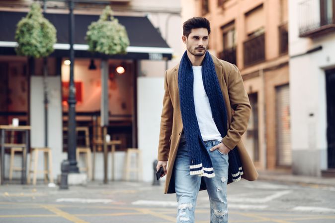 Man in winter coat walking through Spanish town