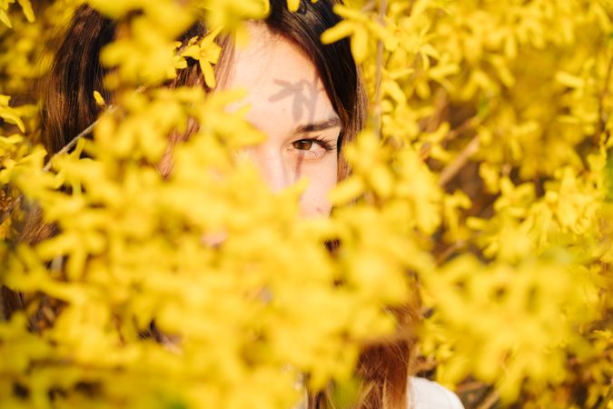 woman hiding amidst yellow flowers