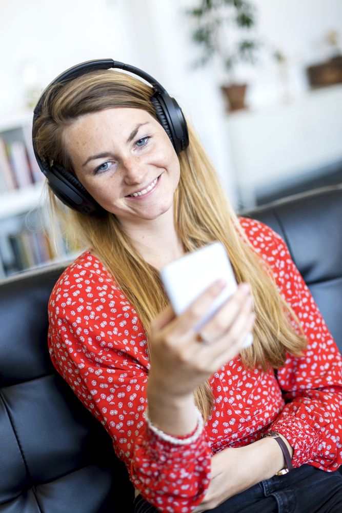 Smiling woman at home relaxing on the couch holding phone