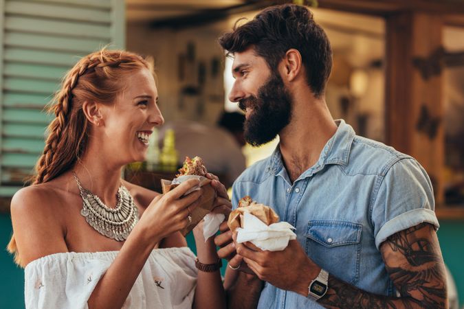 Portrait of happy young couple having burger outdoors