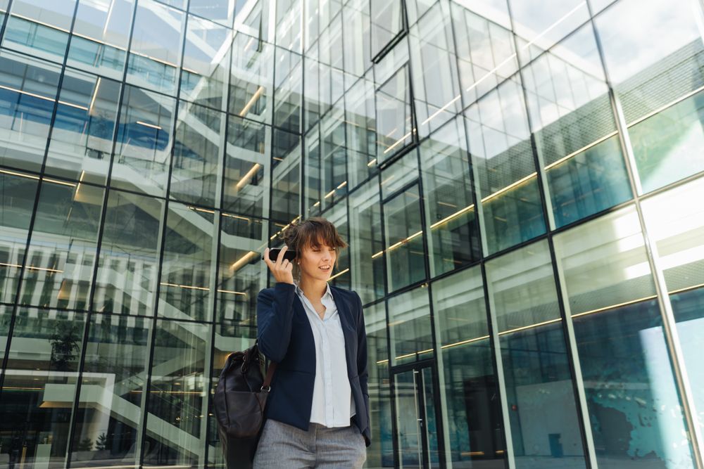 Smiling entrepreneur browsing smartphone outside office building