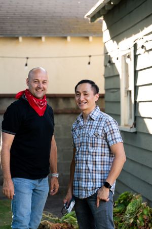 Two men standing outside in backyard smiling and looking at the camera