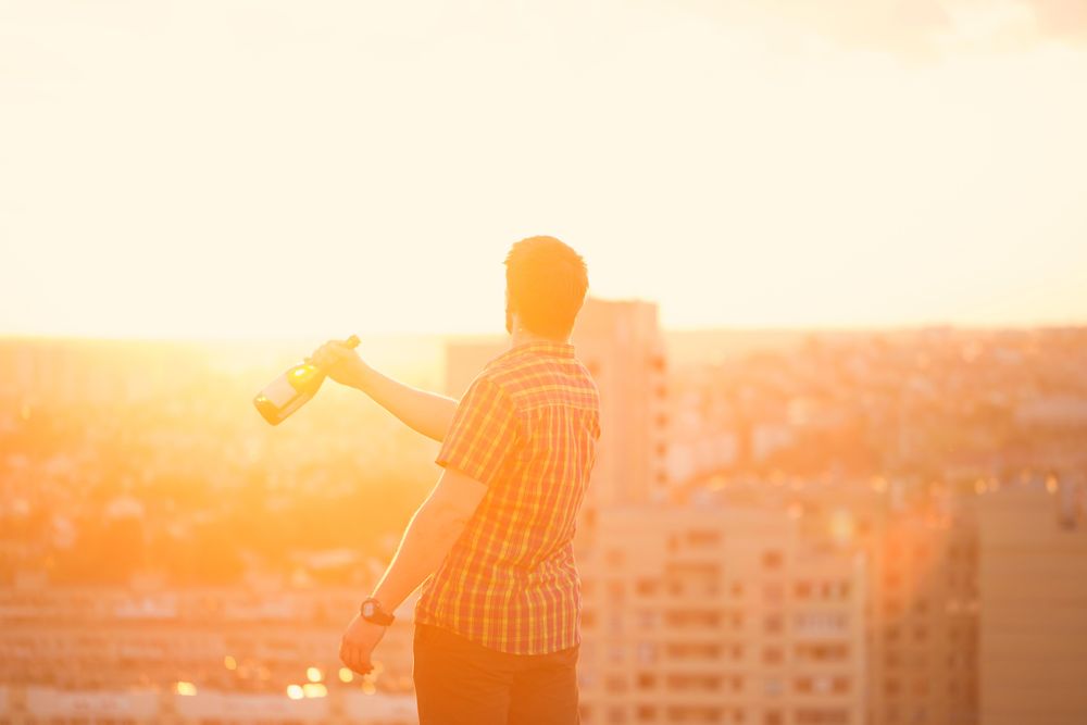 Back of man with bottle of wine at dusk