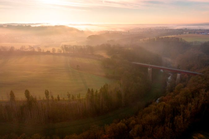 Sunrise scenery, drone aerial view, with railway bridge crossing river in nature