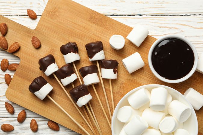 Almond and marshmallow in chocolate on wooden background, top view