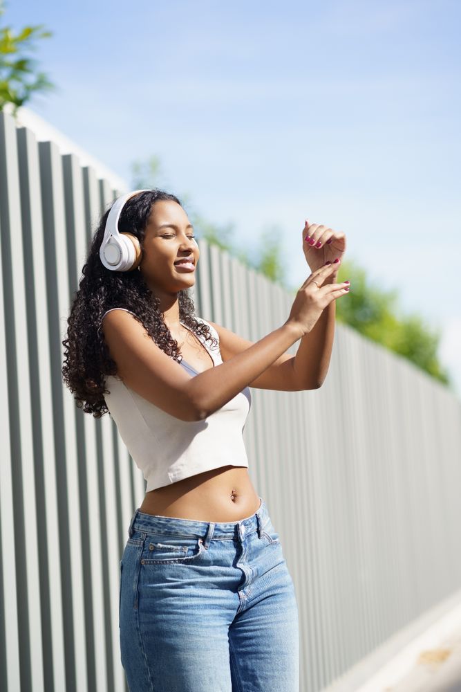 A Joyful Young Woman Dancing Outdoors with Headphones, Embracing the Freedom of Movement