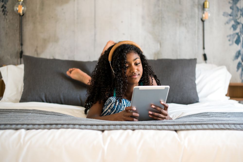 Black girl using tablet in bed