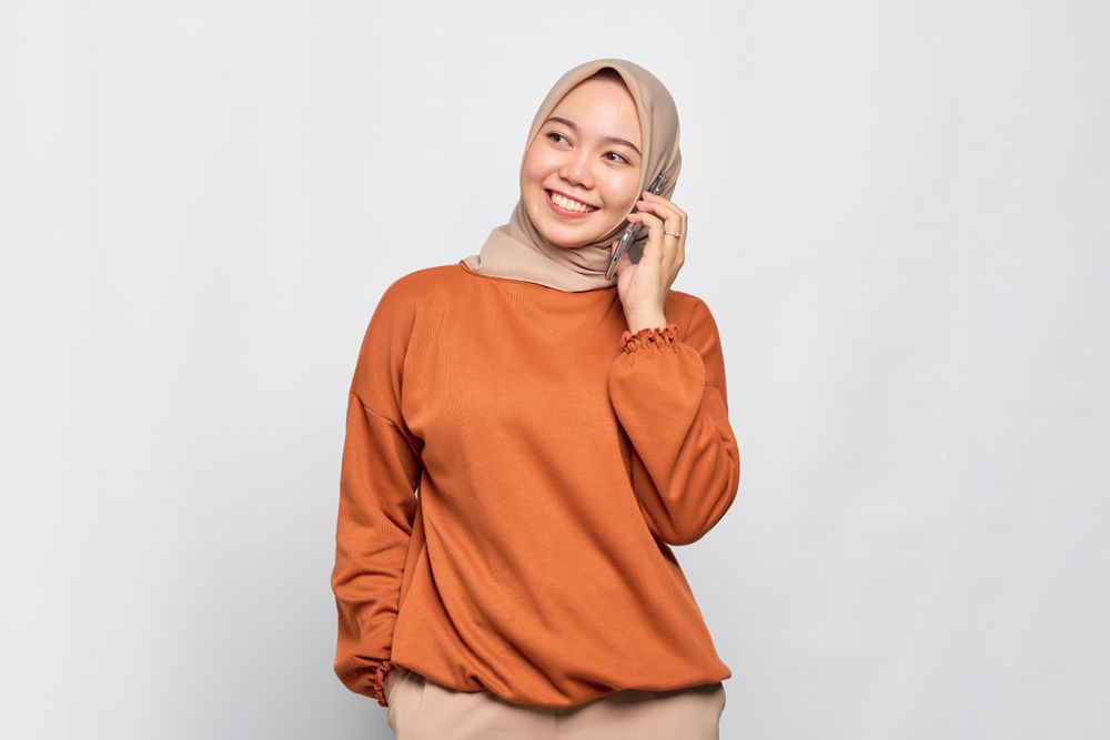 Happy Muslim woman smiling with smart phone to her ear