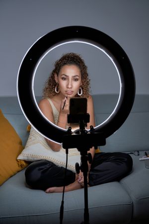 Young woman applying lipstick for lips while shooting tutorial v