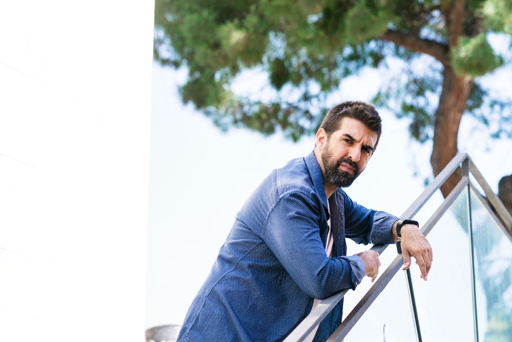 Serious man in denim leaning on outdoor handrail