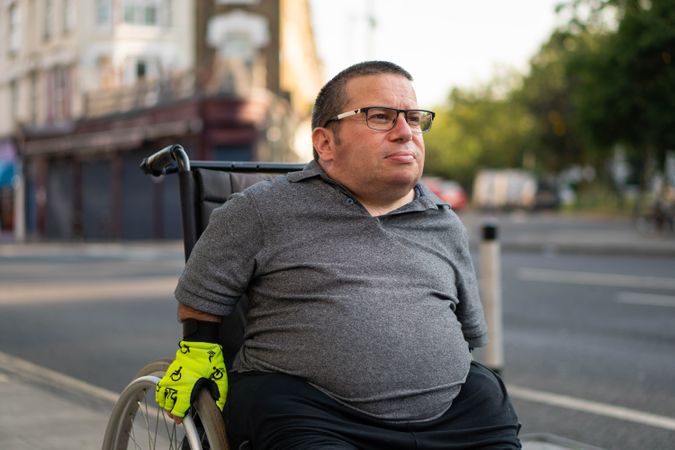 Man sitting in wheelchair on sidewalk in city