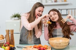 Smiling girl & mother preparing vegetables