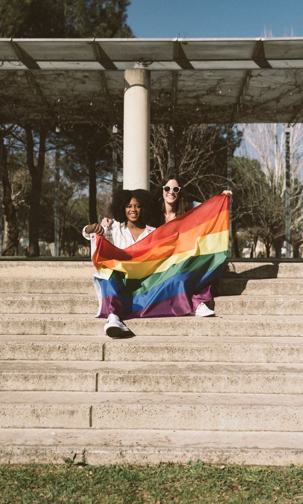 Women with LGBT flag on stairs