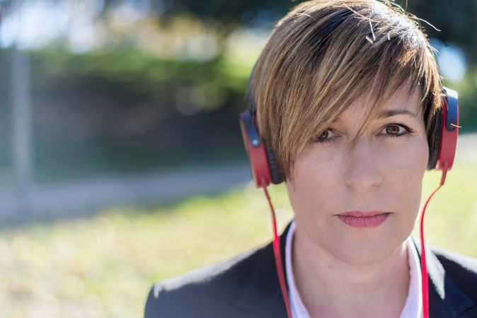 Woman listening to something on red headphones in park
