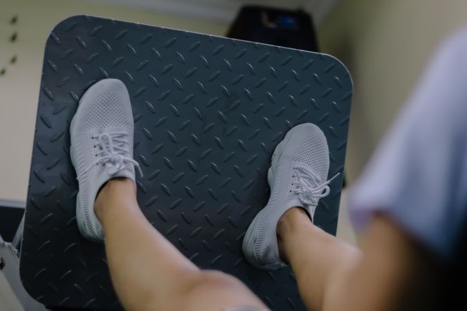 The person's legs are stretched out, pushing against the metal plate of the machine