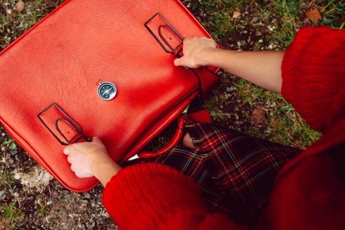 Woman straightening belt on suitcase in road