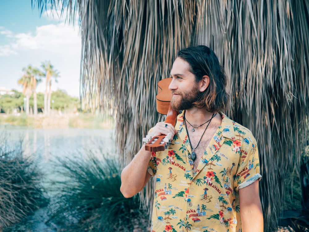 Hipster man in jungle with ukulele