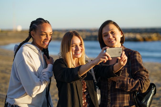 Female friends standing on beach taking a selfie together