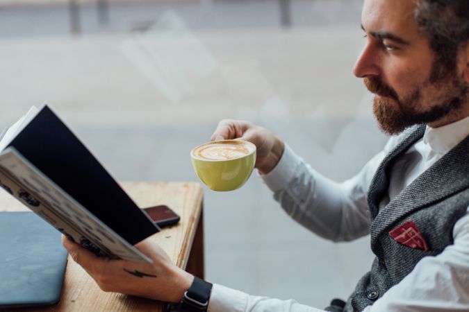 Smartly dressed man with coffee in cafe and book