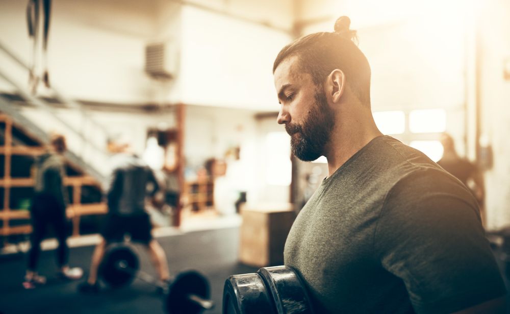 Serious man moving weights in busy gym