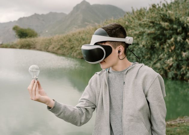 Young teenager with virtual reality glasses holding a light bulb