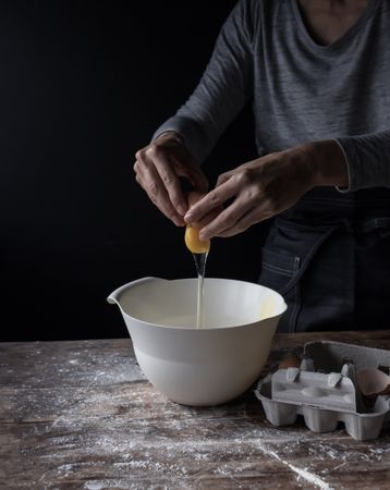 Person cracking egg in bowl on table