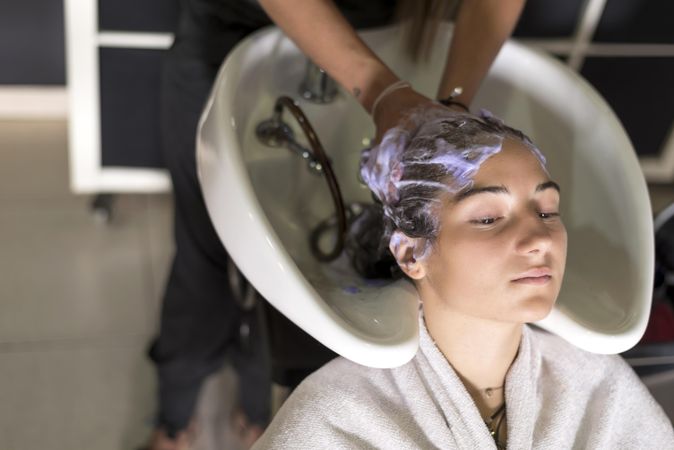Female with head back in sink having hair washed in salon